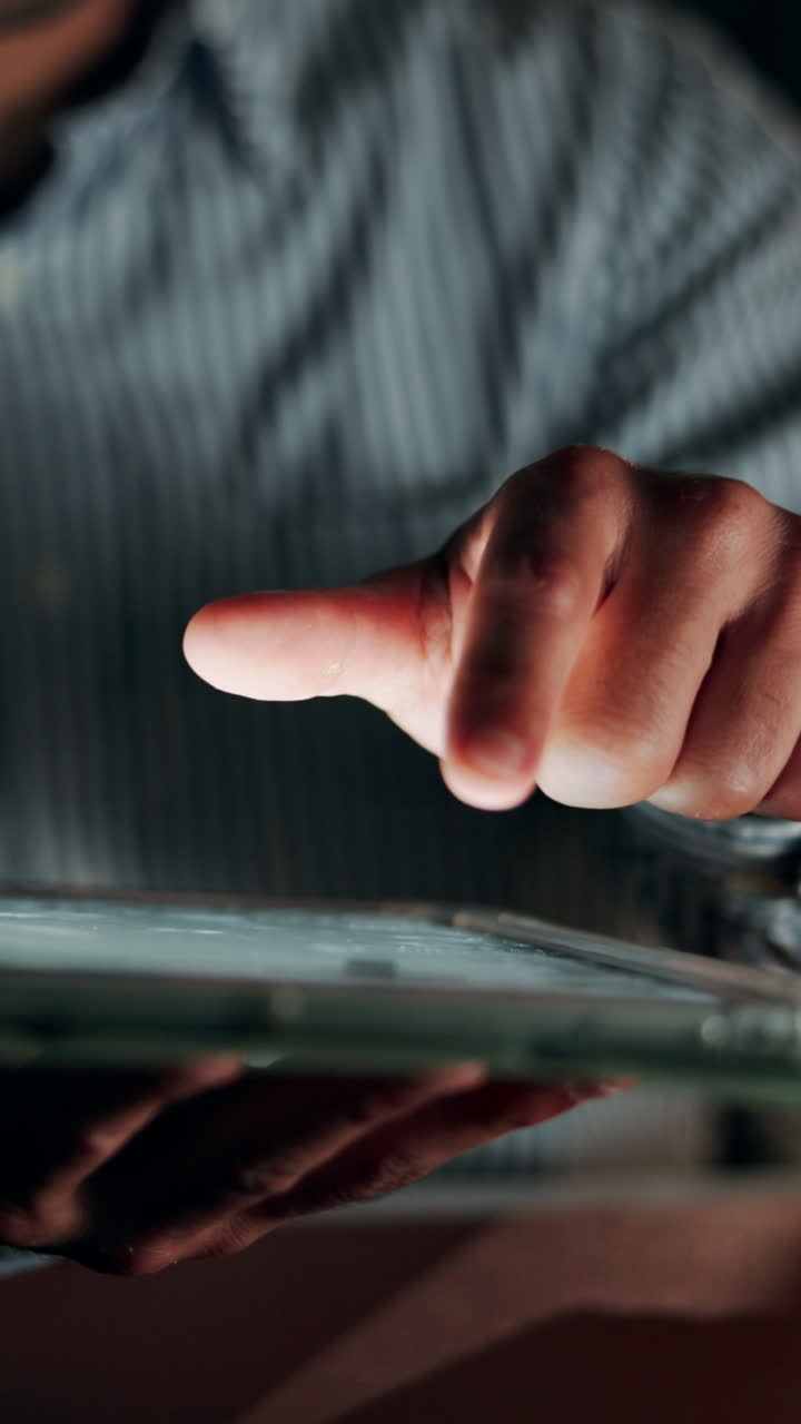 Primo piano di una mano che usa il touchscreen di un tablet in condizioni di scarsa illuminazione