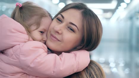 4k cu joven madre hermosa abraza a una hija pequeña están en un centro comercial