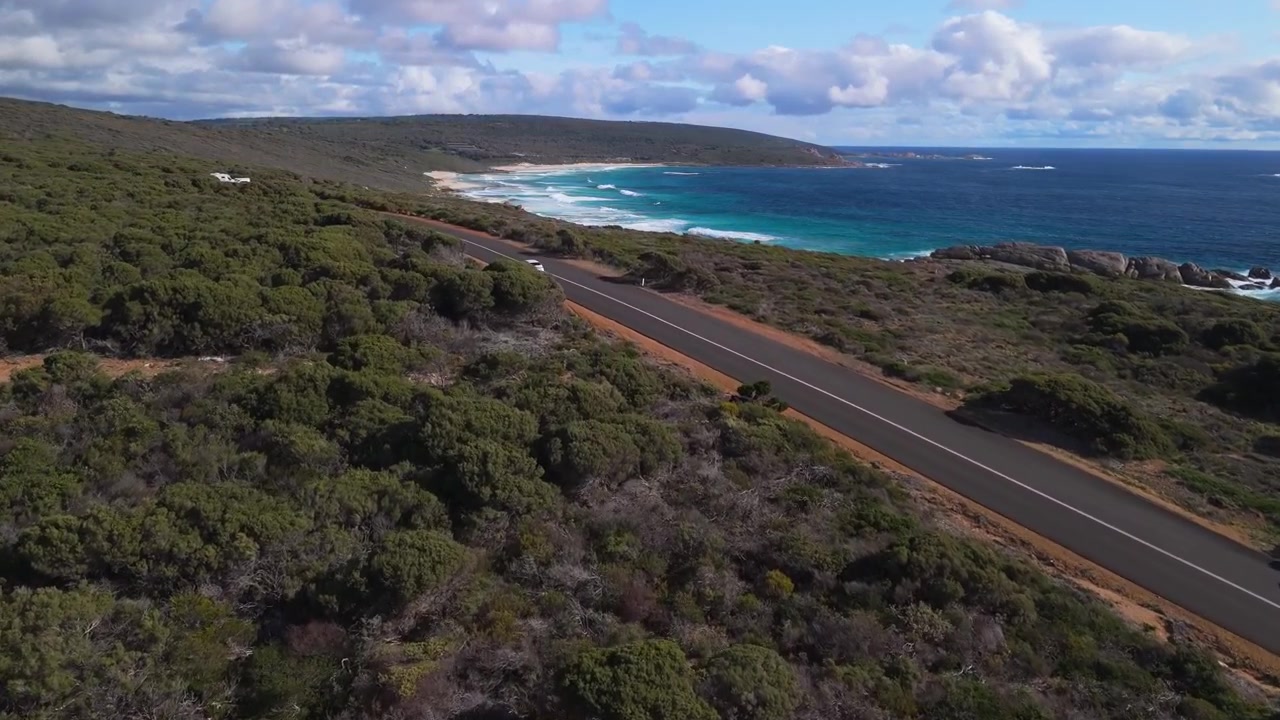 Volo cinematografico di drone sopra un'auto che percorre una strada panoramica a Margaret River, Australia Occidentale.