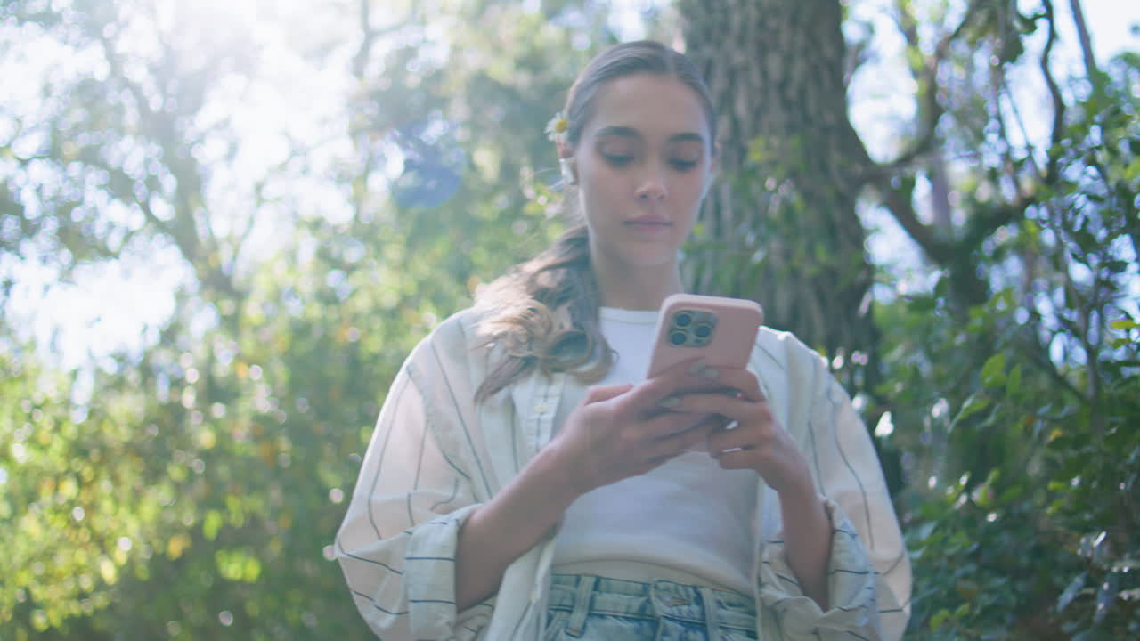 chica mirando pantalla de teléfono móvil caminando parque soleado de cerca. mujer mensajería