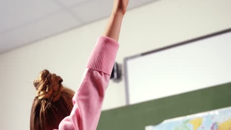 Schoolgirl-raising-her-hand-in-classroom-at-school