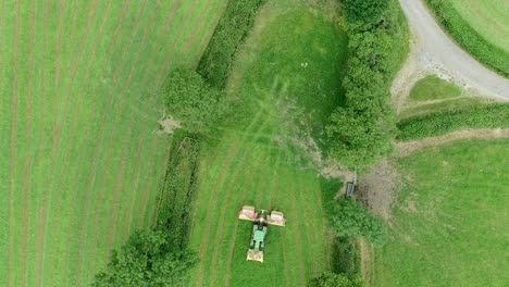 Topdown-of-a-tractor-with-front-and-rear-grass-mowers,-cutting-a-narrow-field