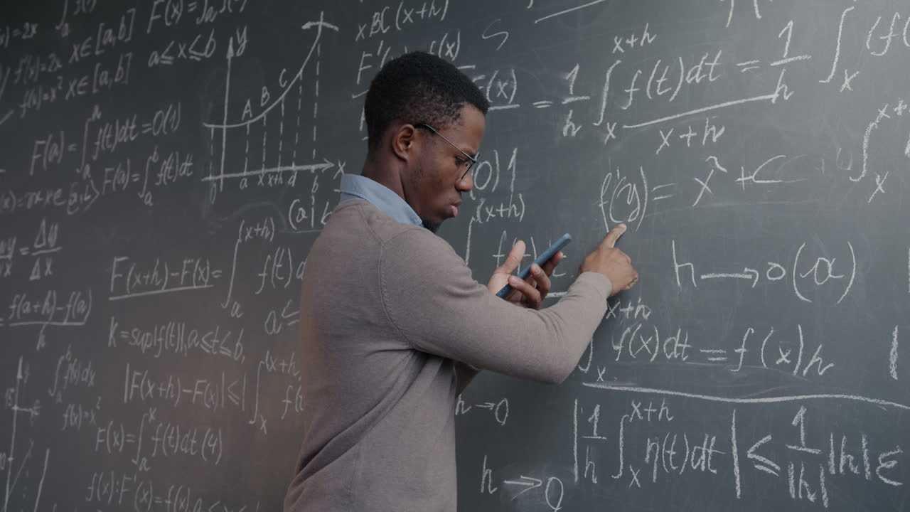 Man working through mathematical equations on a chalkboard
