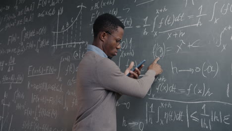 man working through mathematical equations on a chalkboard