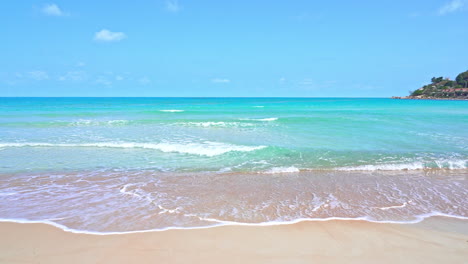 static shot of calm ocean waves reaching shore of a white sand beach during bright sunny day on a tropical island