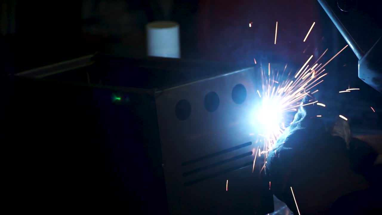 сварка металлической коробки в темной мастерской