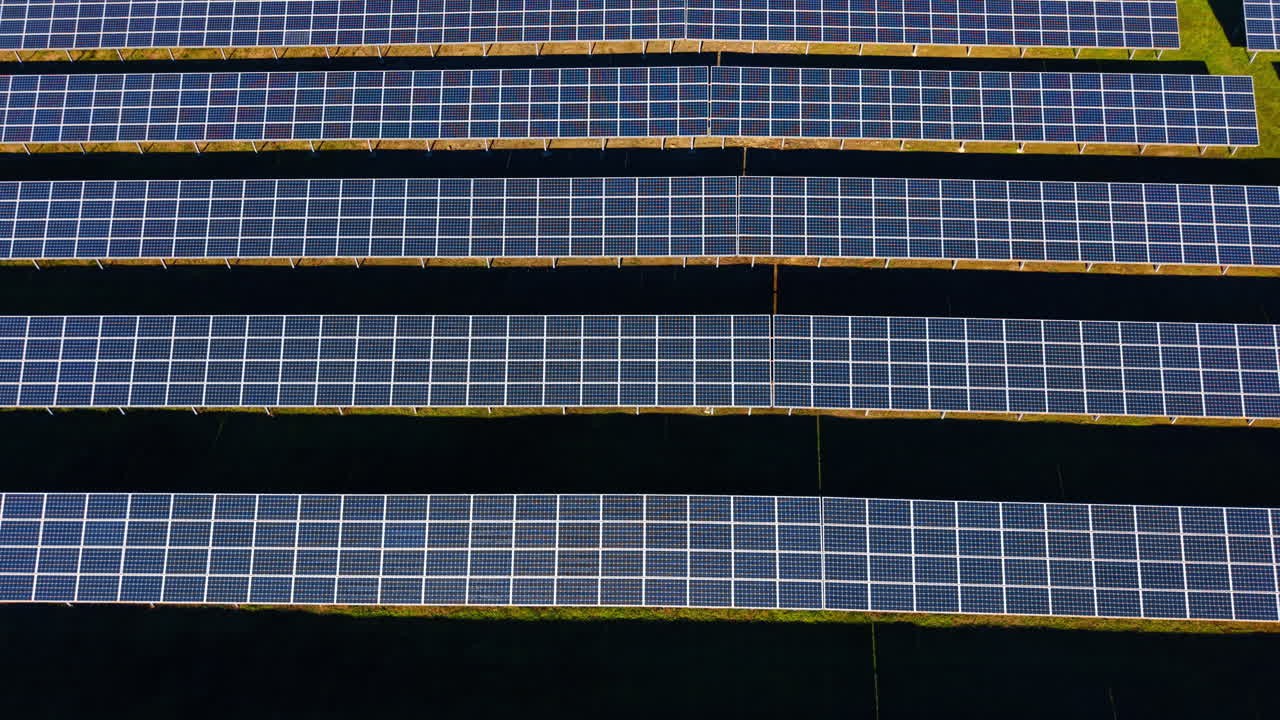 Pannelli solari in una centrale elettrica verde. Prospettiva dall'alto di più file di collettori solari installati su un'area erbosa per la produzione di energia