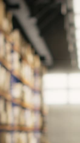 vertical video warehouse clerk placing adhesive shipping labels on boxes in storage room