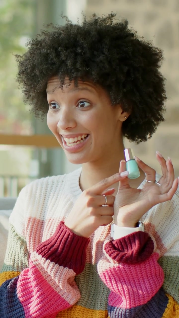 Vertical video: Spotting mint-green polish, woman in striped sweater uncapping, showing at home