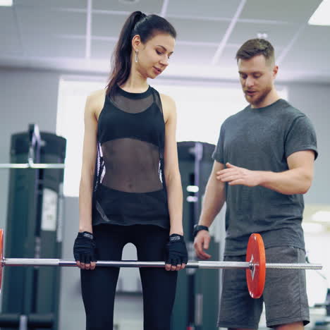 athletic girl with a perfect body lifting metal barbell. personal fitness instructor. personal training.