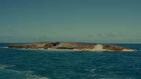 Pazifikwellen-Jagen-An-Die-Küste-Dieser-Felsigen,-Einsamen-Insel-Mit-Ihrer-Eigenen-Natursteinbrücke,-Die-Durch-Jahrelange-Erosion-In-Hawaii-Entstanden-Ist