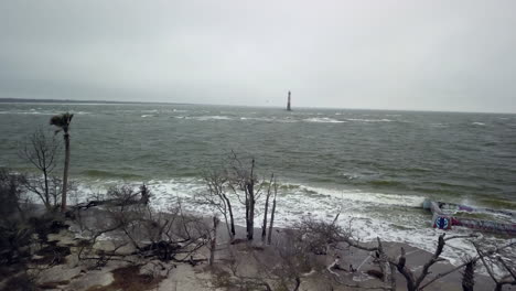 Luftaufnahme-Des-Leuchtturms-Von-Morris-Island-In-Der-Ferne-Mit-Folly-Beach-Und-Dem-Atlantischen-Ozean-Im-Vordergrund