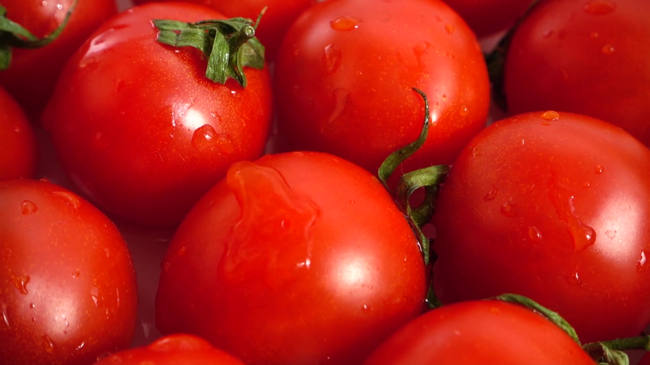 Tropfen fallen auf Tomaten. Zeitlupe
