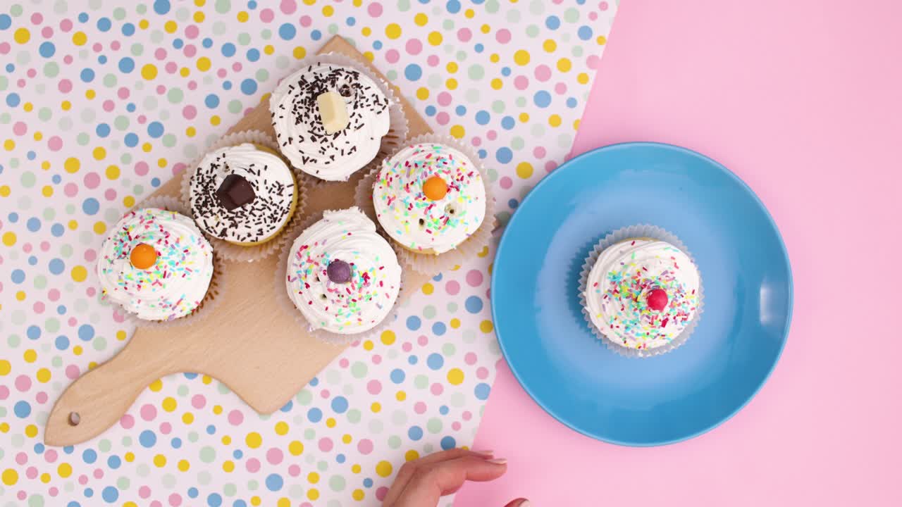 Hand take one cup cake from cutting board and put on plate. Stop motion