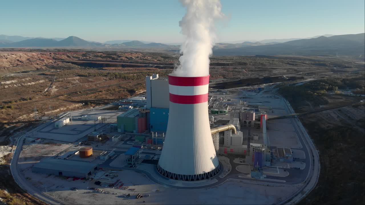 Fumo di una centrale termoelettrica a carbone ripreso da drone, con inquadratura che segue il camino e panoramica verso il basso al tramonto.