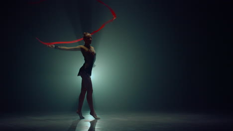 gymnast showing elements with ribbon. woman practicing rhythmic gymnastics.