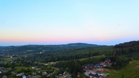 aerial view over a village, in the carpathian mountains, colorful dusk sky, ukraine - dolly, drone shot