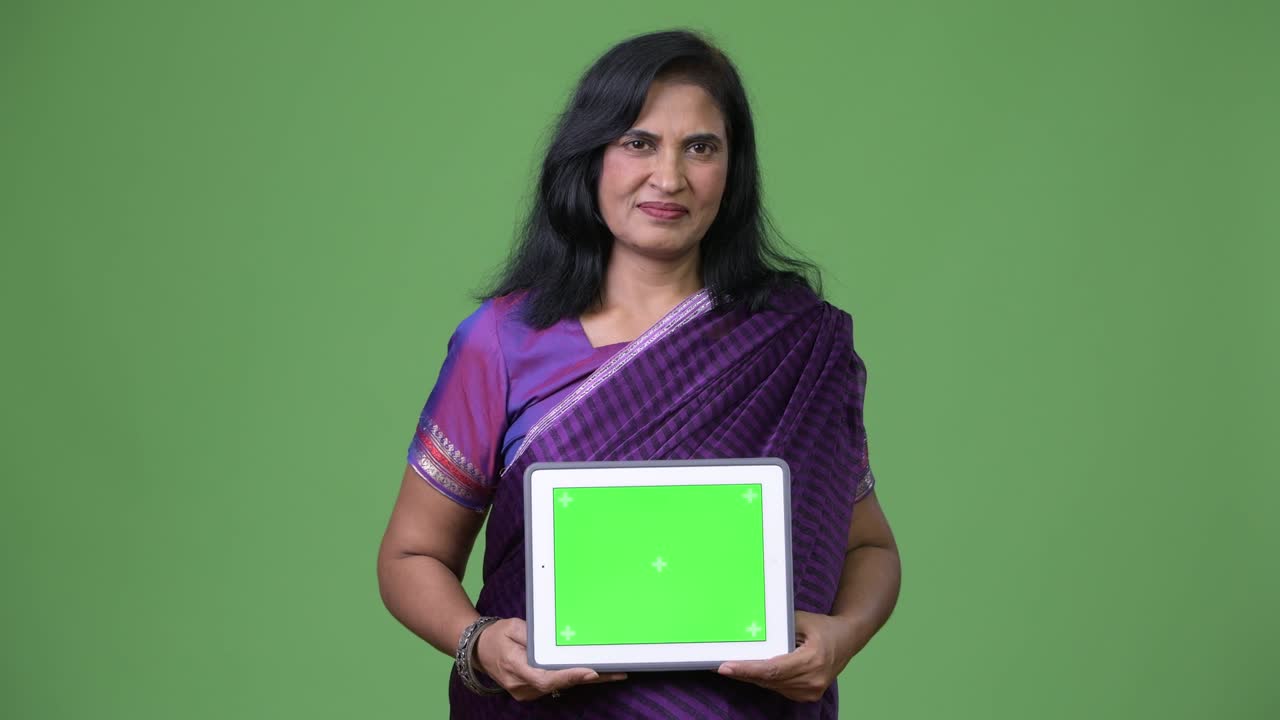 зрелая красивая индийская женщина показывает цифровой планшет