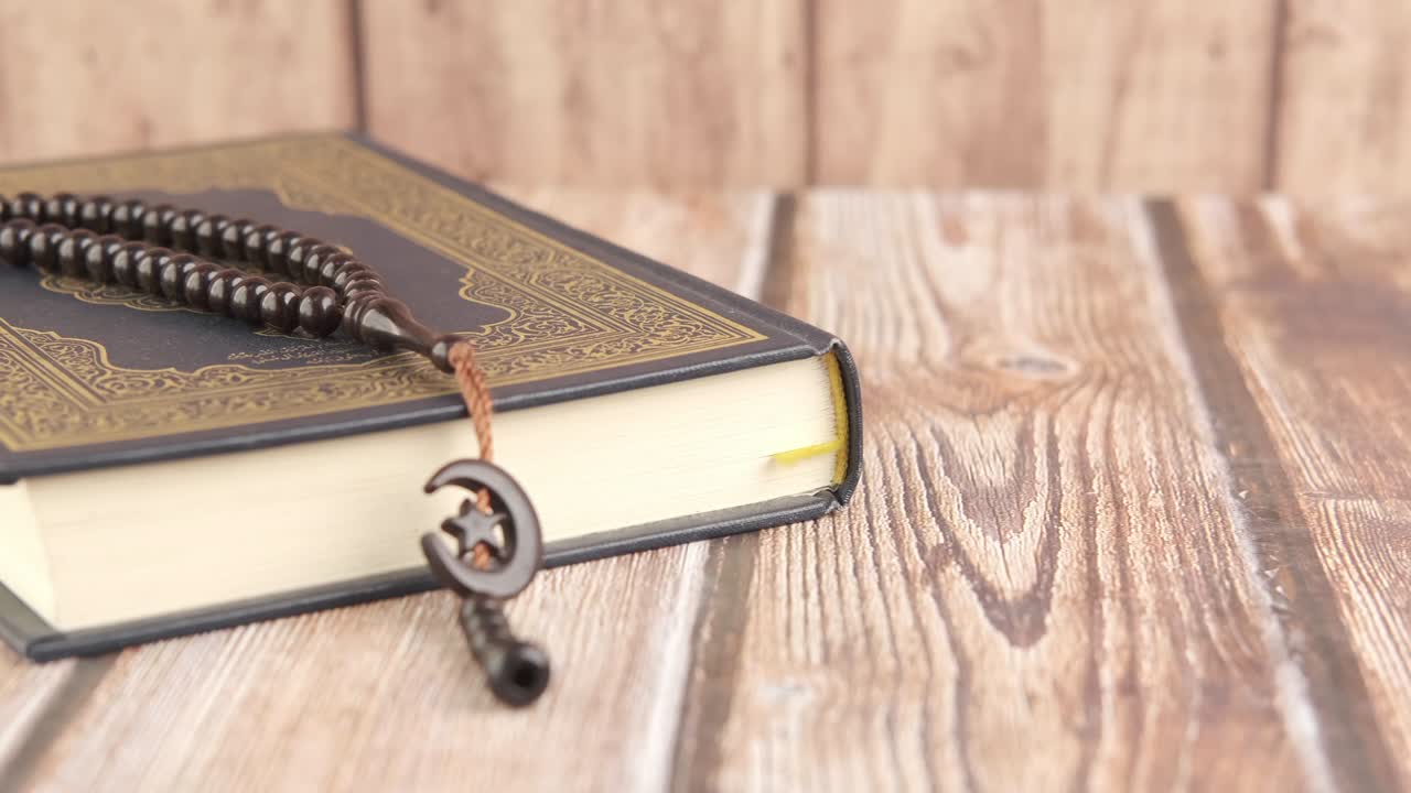 Holy book Quran and prayer beads on table, close up.