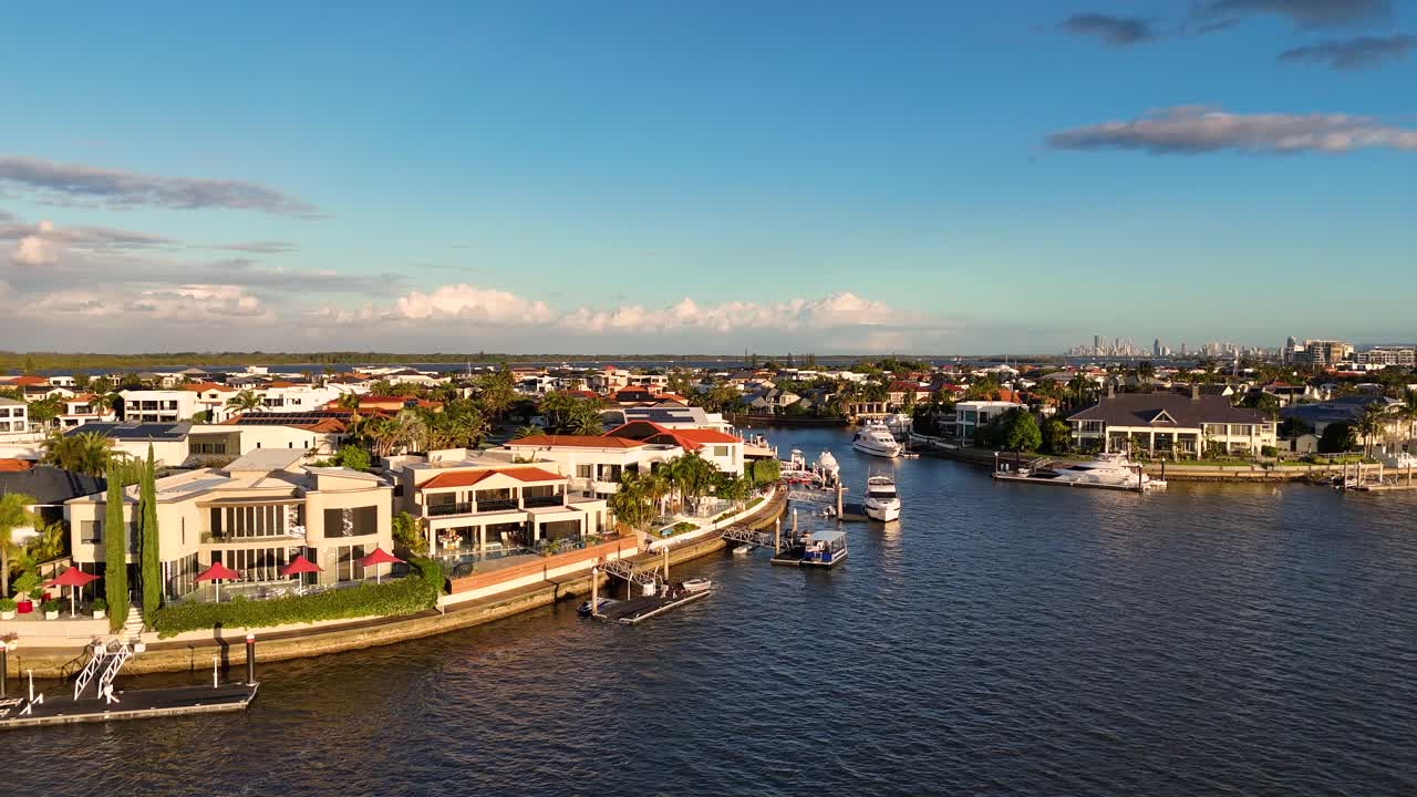 Drone footage captures luxury waterfront homes and boats on Gold Coast's Broadwater during sunset, showcasing serene coastal beauty