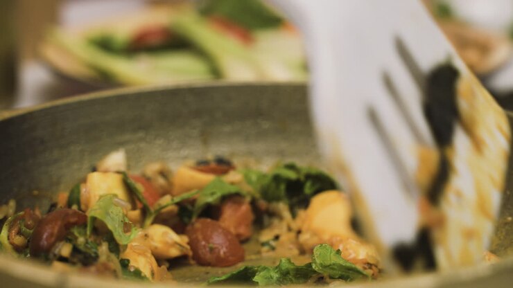 Vista de cerca de comida japonesa en la sartén mientras el cocinero la mueve con una espátula ranurada 1