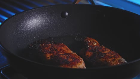 flipping chicken breast cooking in a pan