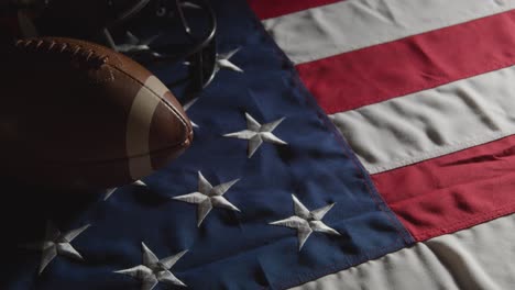 low key lighting studio shot of american football with helmet on stars and stripes flag