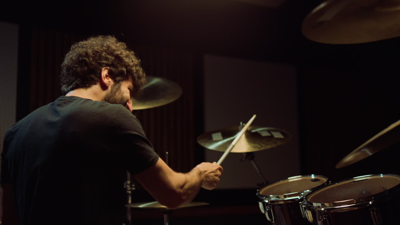 Cheerful artist hitting drum cymbals in studio