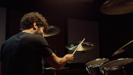 cheerful artist hitting drum cymbals in studio