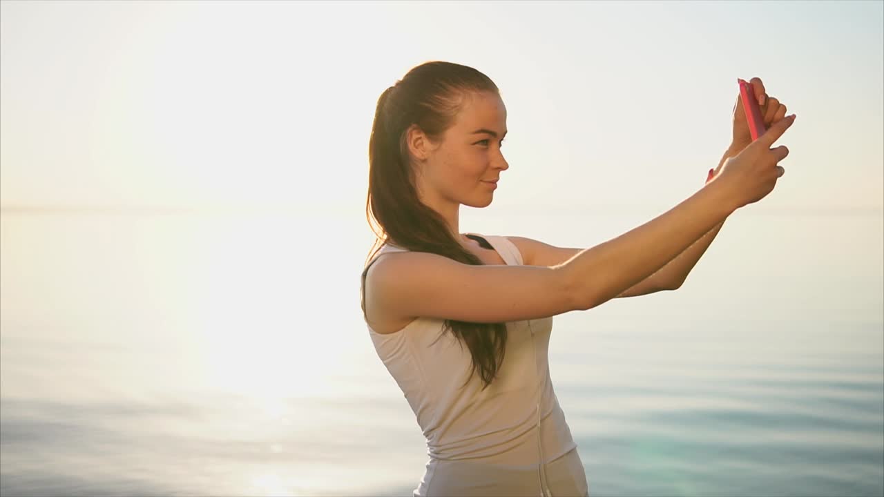 Woman taking a selfie at the beach at sunrise