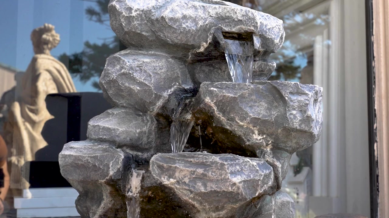 Una fontana rocciosa a cascata con acqua che scorre - Ripresa con panoramica verso il basso.