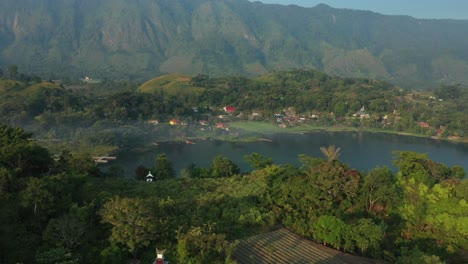 aerial drone footage of cliffs, resort hotels, and villages along the shoreline of lake toba in north sumatra, indonesia