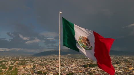 Echte-Mexikanische-Flagge-Weht-Auf-Einem-Hügel-In-Einer-Mexikanischen-Stadt-Oaxaca-Bei-Dramatischem-Sonnenuntergang