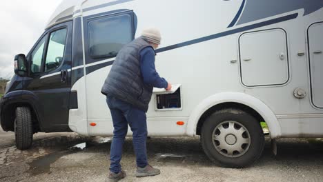 a man pulls a toilet waste container out of a caravan