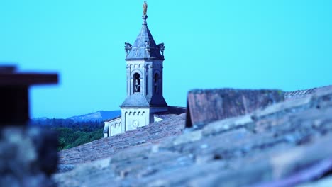 small beautiful church tower protrudes between houses in a village in france at sun boulbon