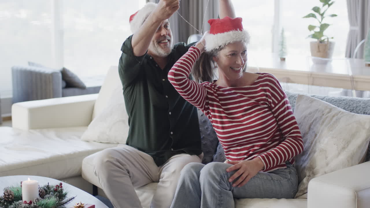 hombre caucásico de mediana edad con sombrero de santa poniendo cadena en el cuello de una mujer en navidad, cámara lenta