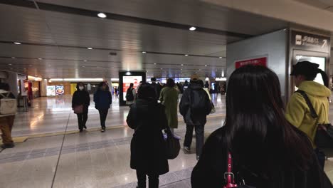 crowds of people walking through a busy station