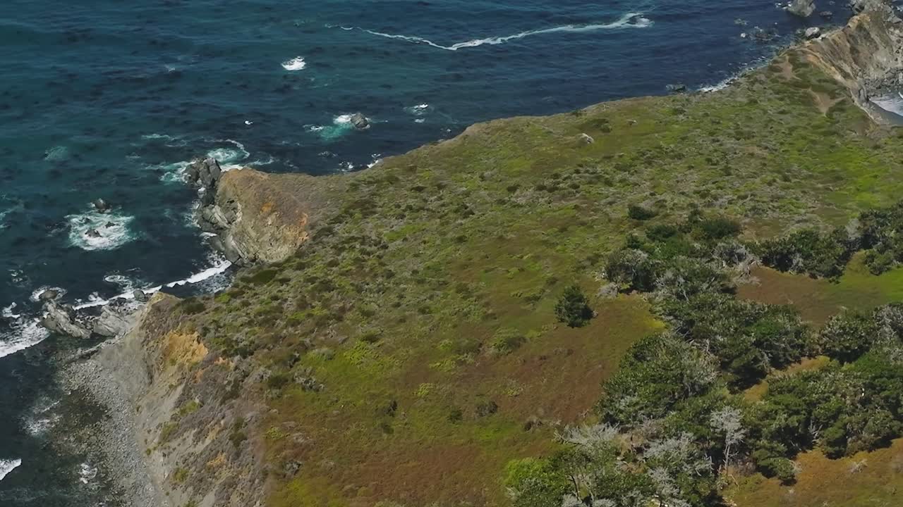 Vista aerea di un'area costiera in California con terra verde e acqua blu.