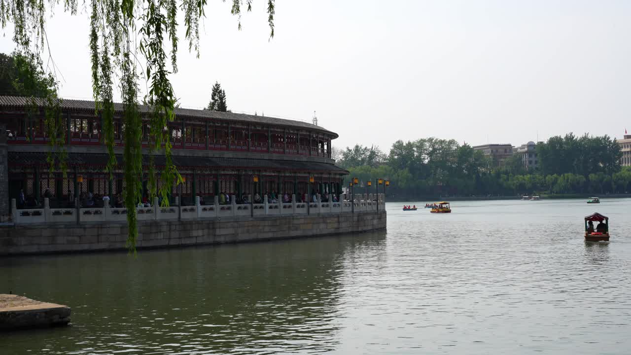 лодки, плавающие вблизи острова чионгхуа в парке бейхай в спокойный день, с видом на ивы