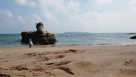 Fisherman-enters-the-water-to-join-his-colleague-and-casts-his-het-near-a-large-rock-formation-on-a-remote-Andaman-island-in-India