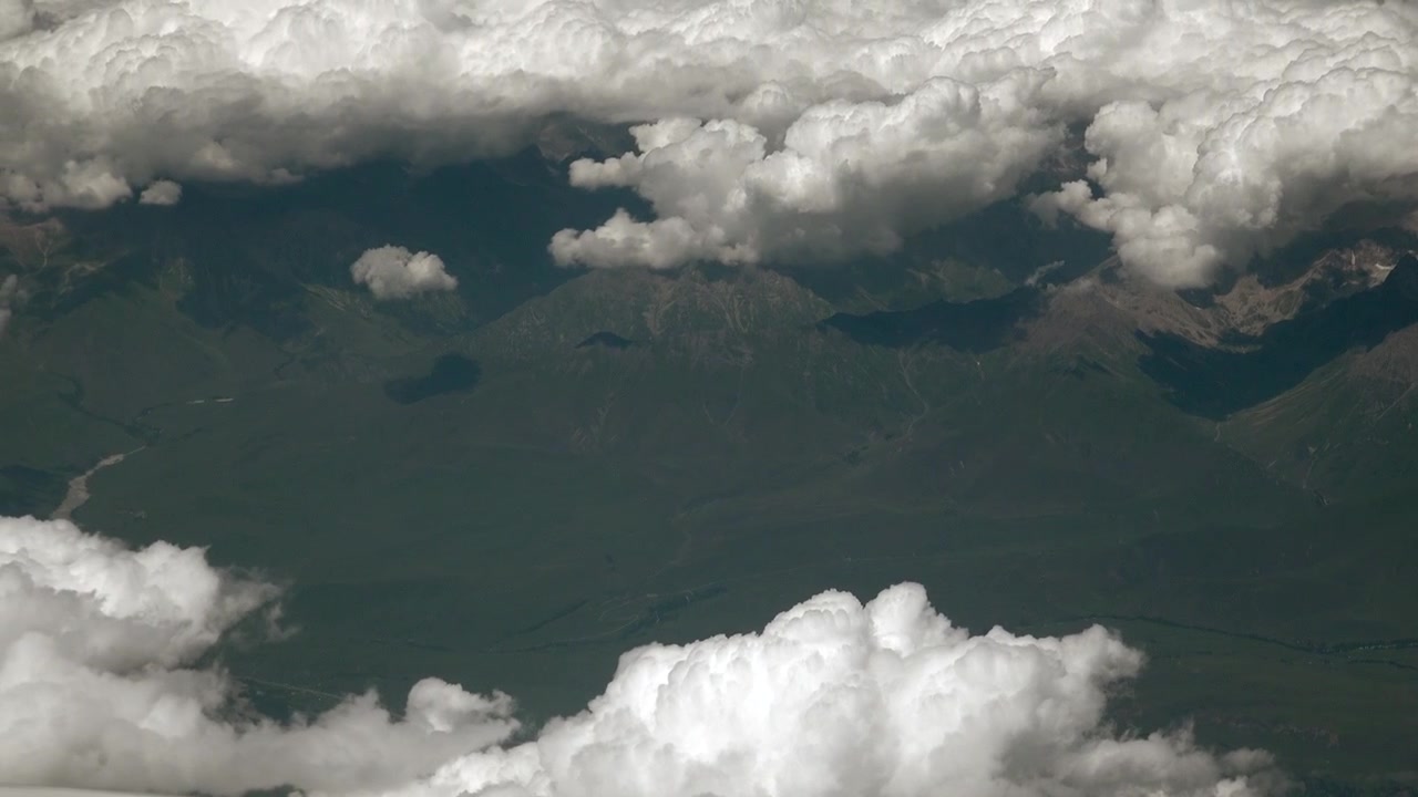 Aerial View of Mountain Range Beneath Fluffy White Clouds