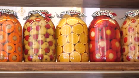 colorful preserved fruits in glass jars on a wooden shelf