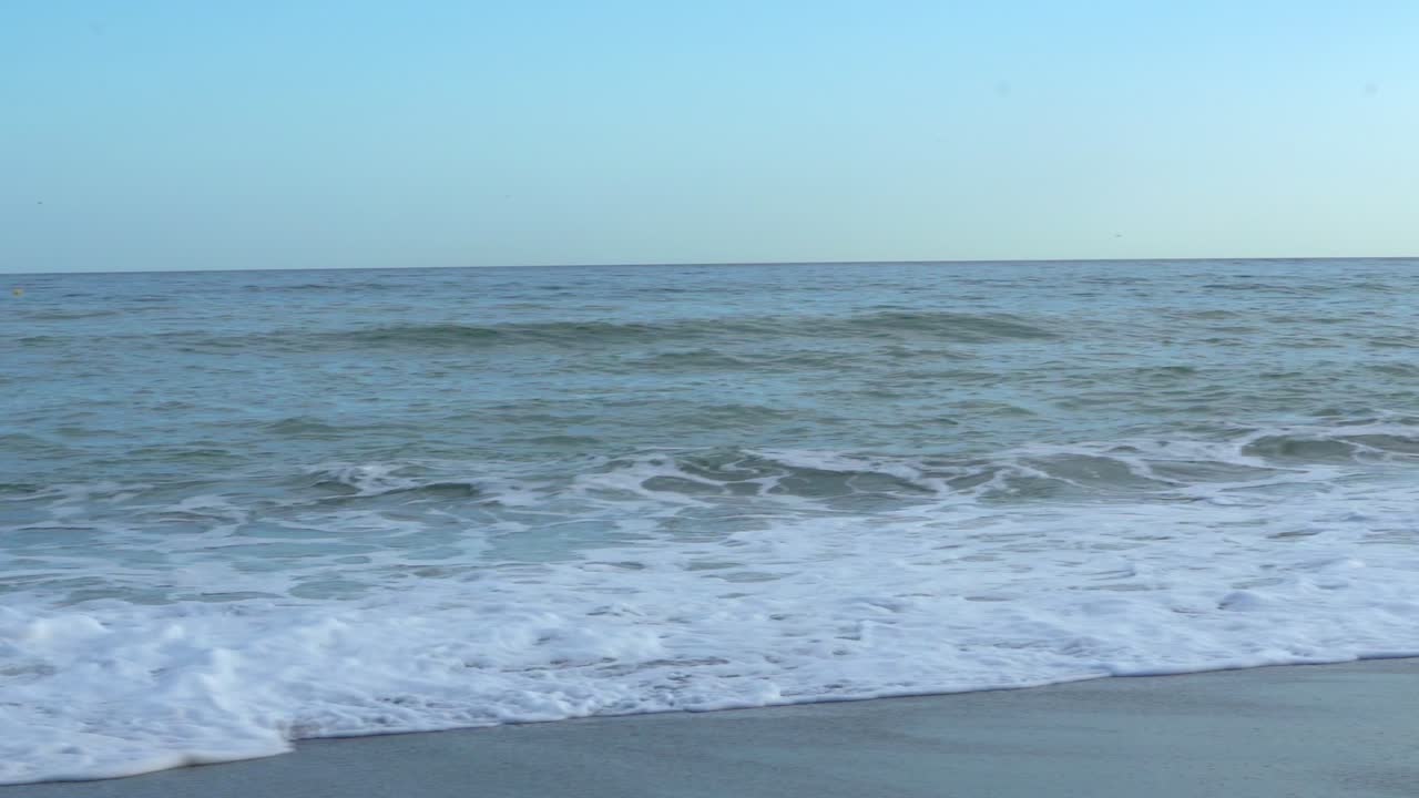 View on Malaga port from Malagueta beach, panning RIGHT to LEFT, as waves crashes