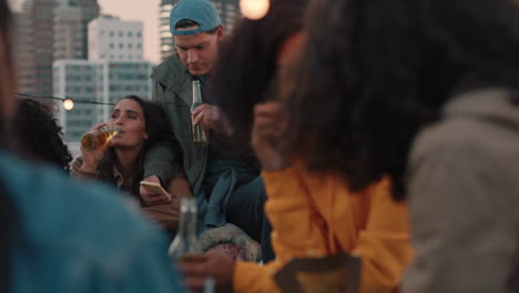 group of young friends enjoying rooftop party celebration drinking alcohol having fun chatting students sharing summer vacation excitement at sunset