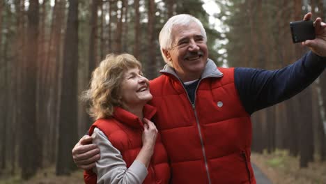 Glückliches-Seniorenpaar-Macht-Selfie-Während-Ihres-Wintersporttrainings-Im-Wald