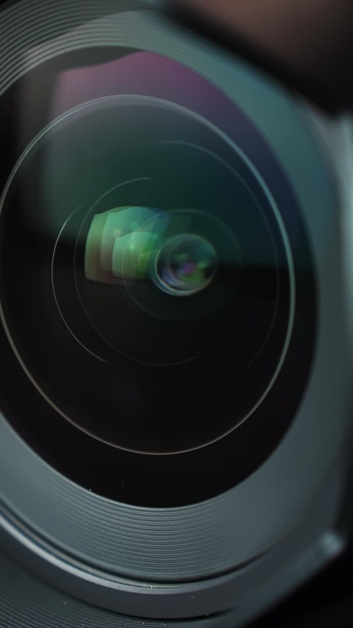 Primo piano macro di un obiettivo fotografico che ruota mentre l'anello di messa a fuoco gira, con riflessi colorati e cerchi concentrici nel vetro—b-roll tecnologico elegante per la produzione cinematografica e pubblicità di attrezzature fotografiche