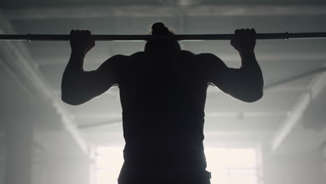 man doing wide grip pull ups on bar. athlete pumping arm muscles with chin ups