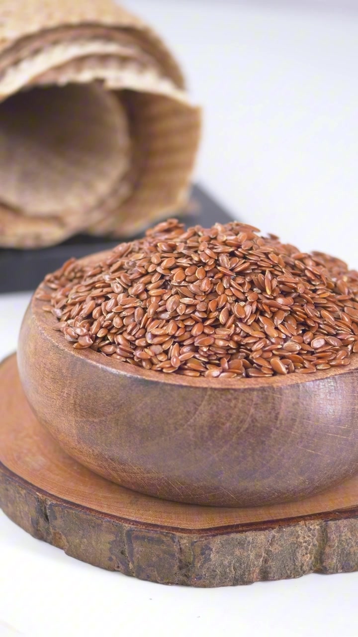 Healthy Flax Seeds in a Wooden Bowl on White Background