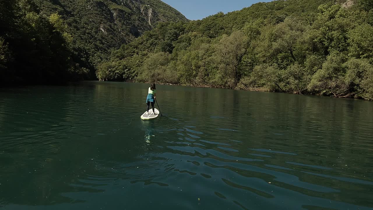 молодая спортивная девушка гребет на суперборде вдоль каньона