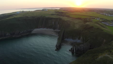 Eine-Luftaufnahme,-Die-Die-Küste-Von-Pembrokeshire-In-Der-Nähe-Von-Manorbier-Beach-Mit-Kirchentürbucht-Bei-Sonnenuntergang-An-Einem-Ruhigen-Sommertag-Zeigt